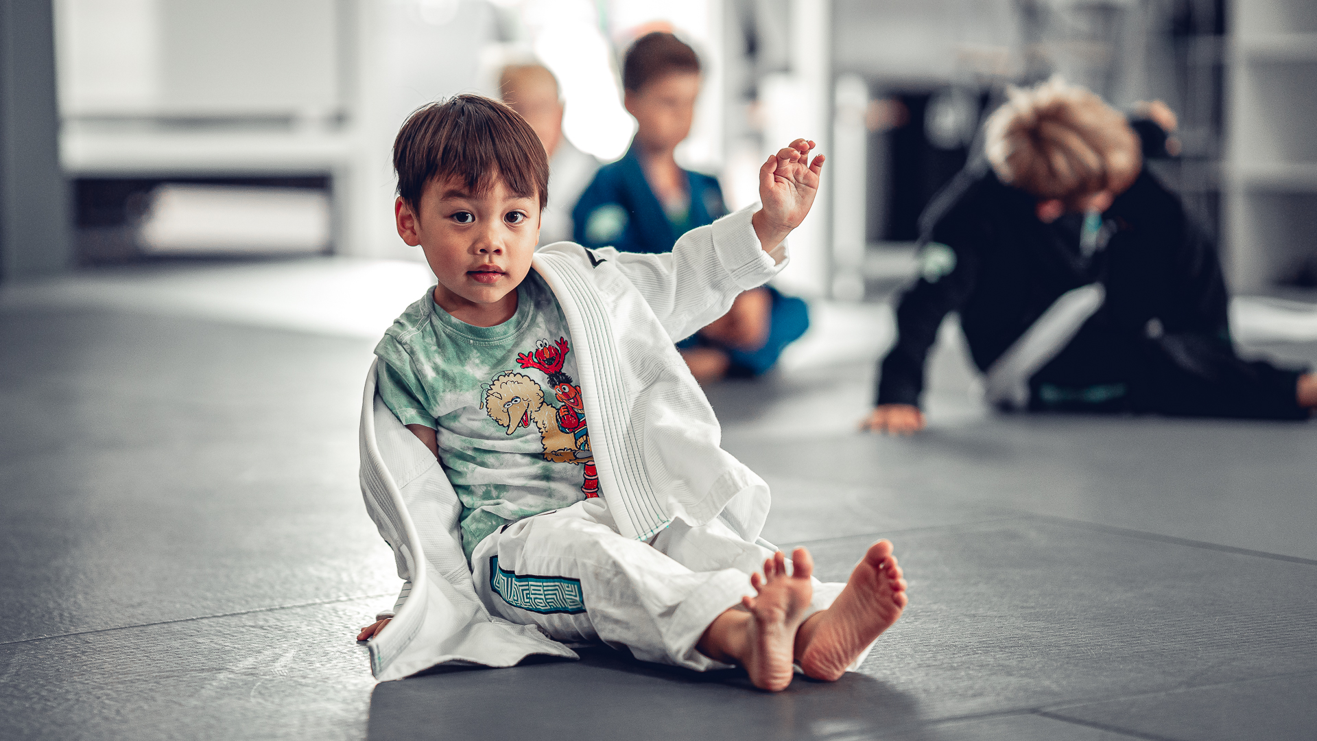 A young Del Mar Jiu-Jitsu Club student sitting comfortably on the academy mat